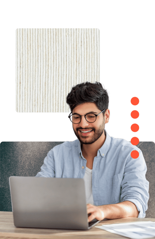 A person in a light blue shirt is working on a laptop at a desk, with a fabric swatch and colored dots in the background.