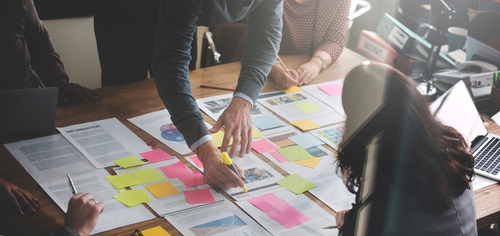 people going through plans laid out on a desk