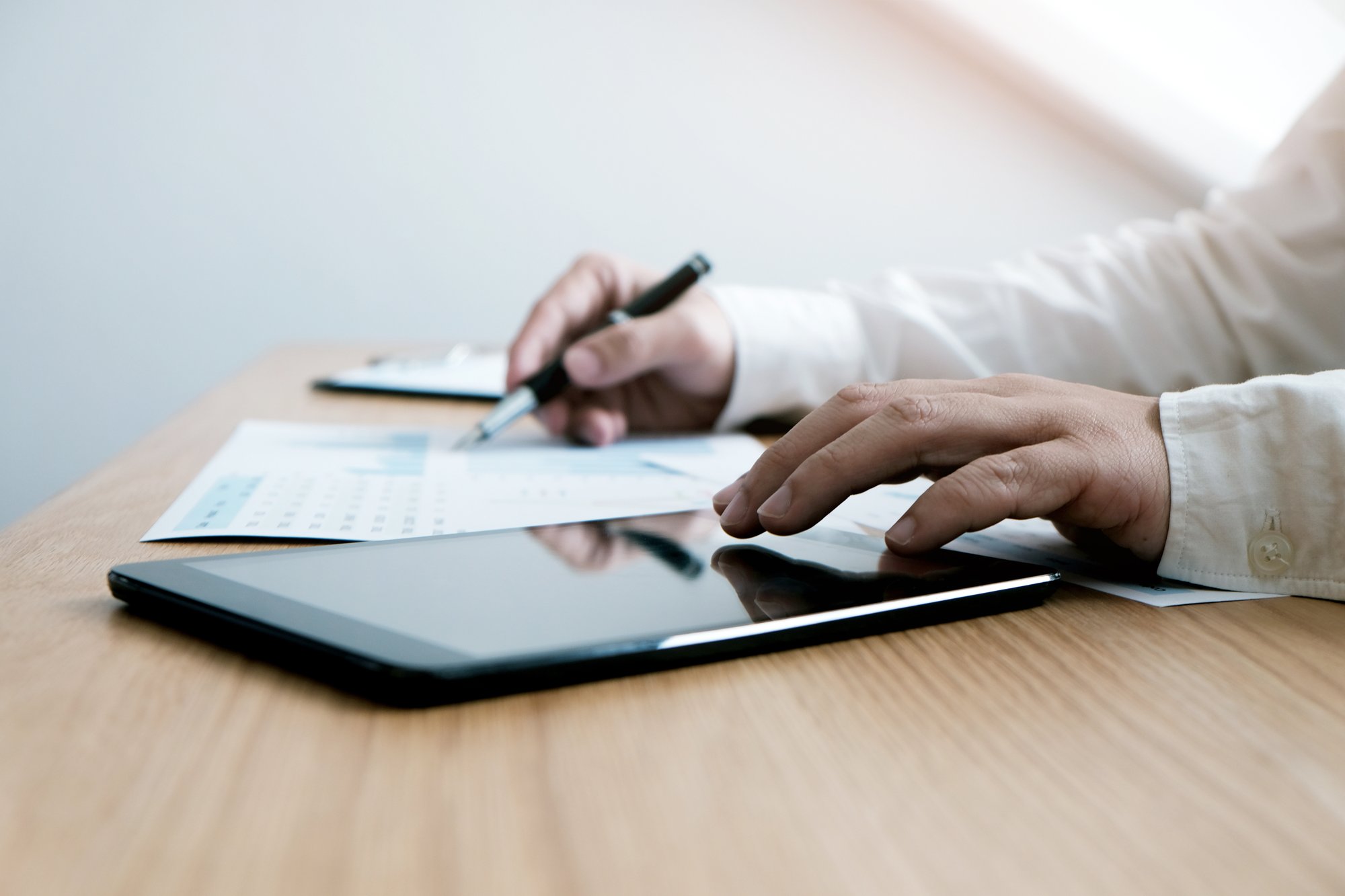 person working on a tablet and signing papers