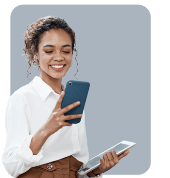 Woman smiling while checking her phone, holding a tablet